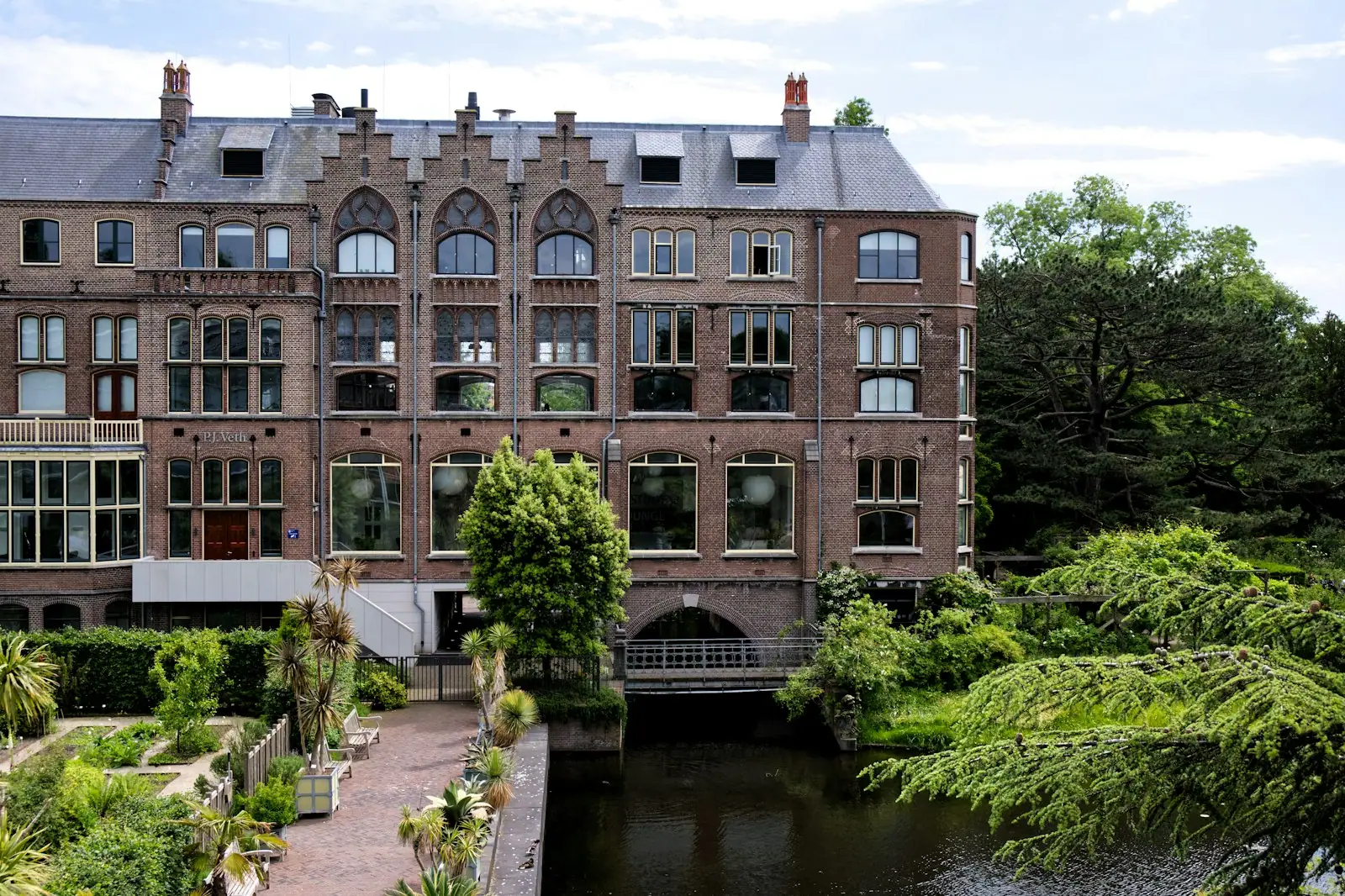 A large brick building with many windows next to a river