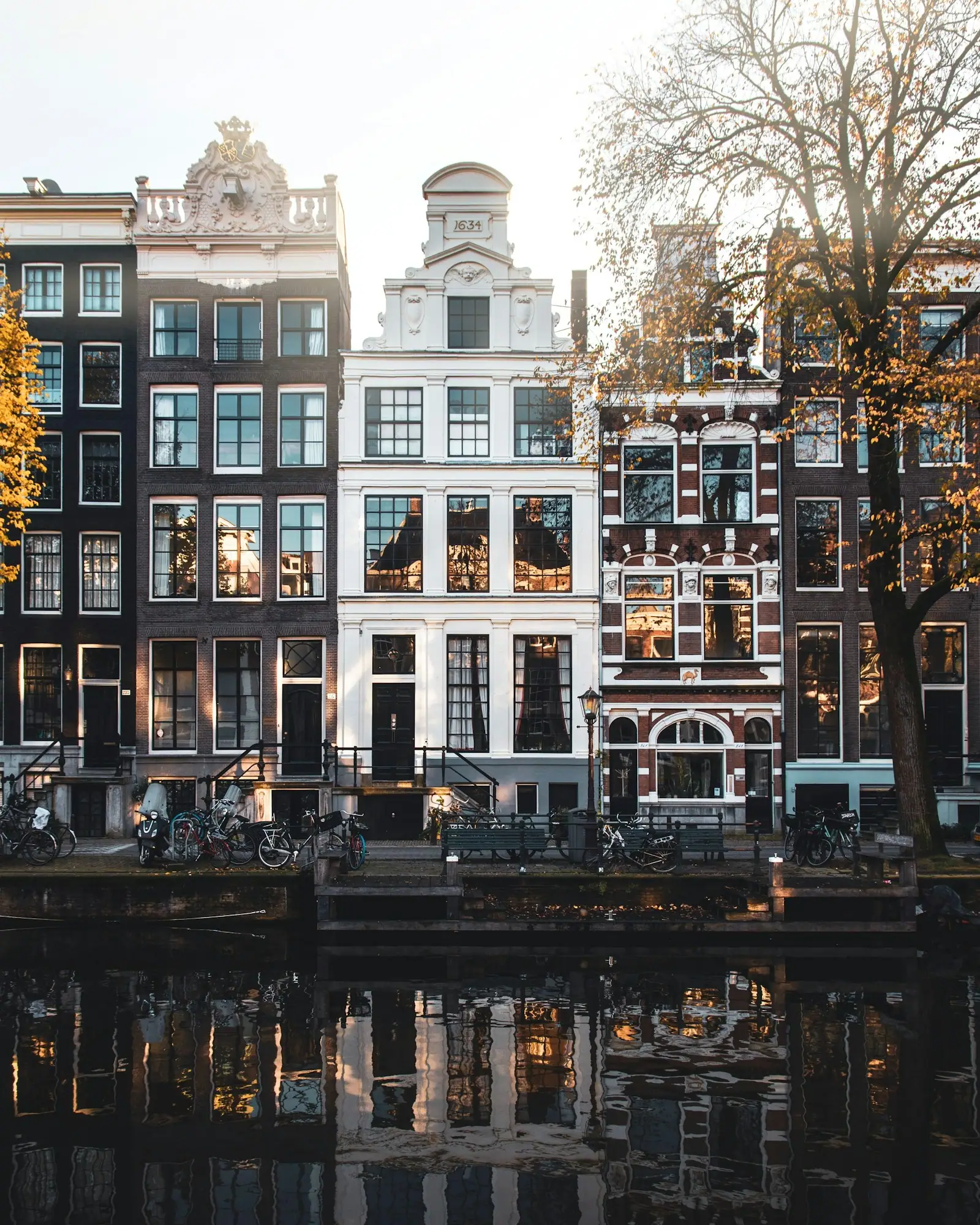 Narrow canal houses with gabled facades reflecting in the water in Amsterdam