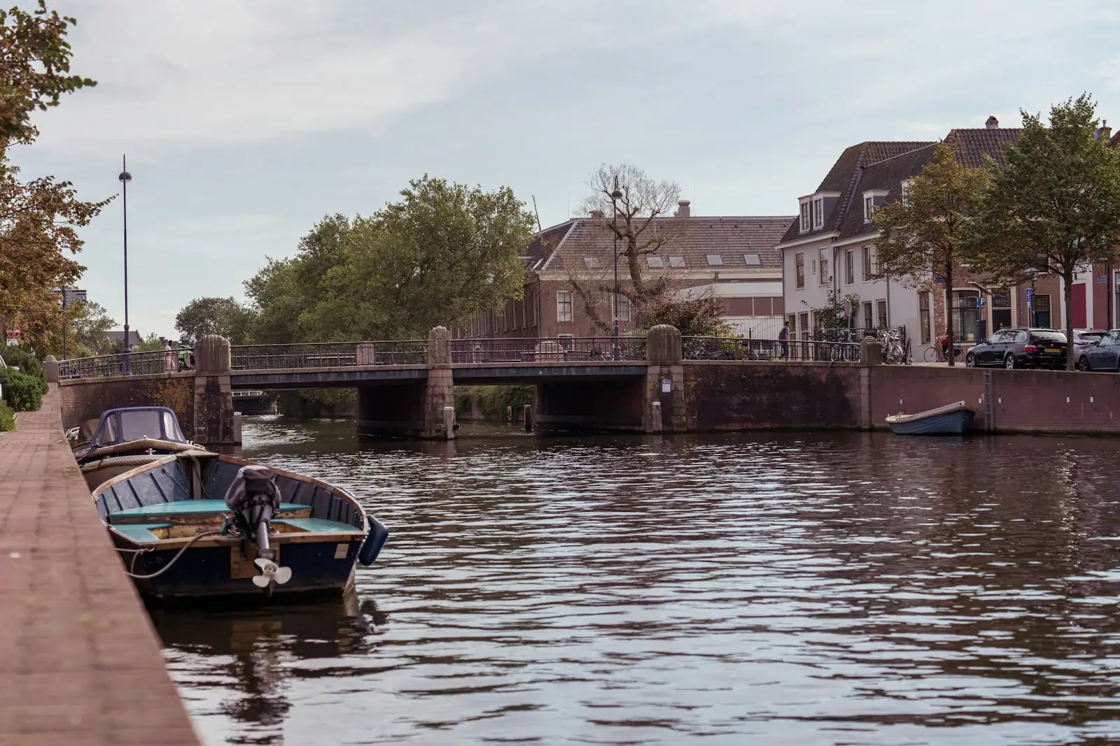 A boat sitting on the side of a river next to a bridge