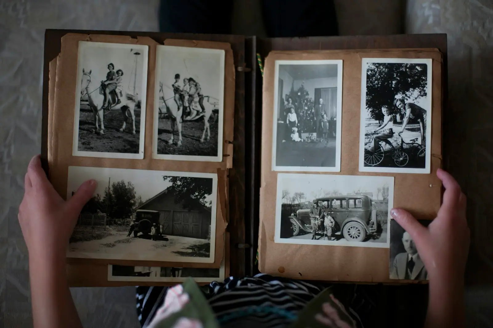 Person opening photo album displaying grayscale photos