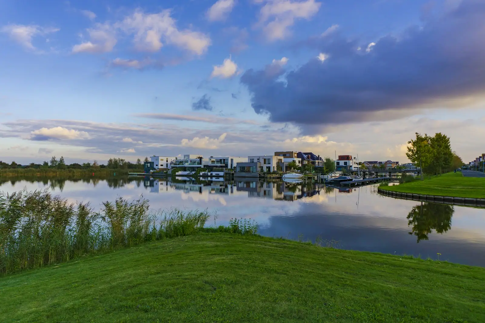Green grass field near body of water under blue sky during daytime