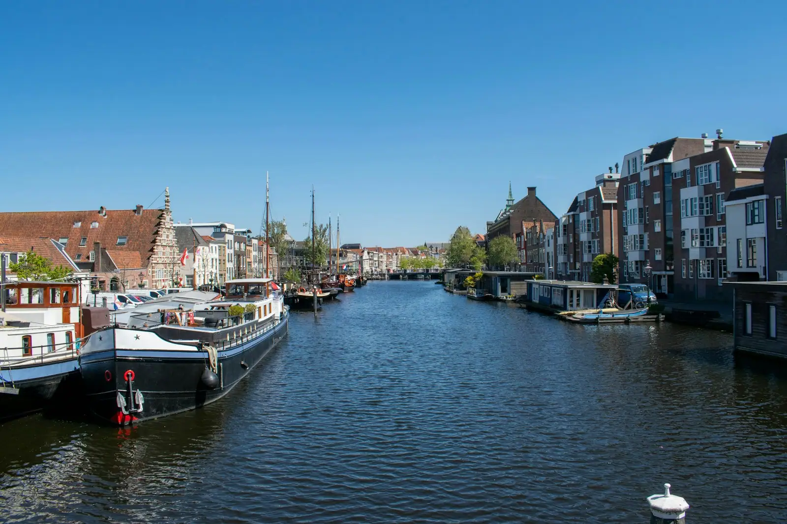 Historic buildings and boats line a calm city canal