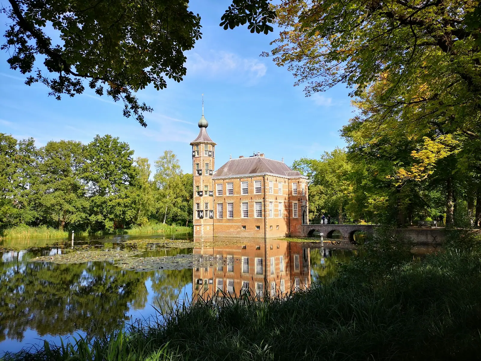 Brown concrete building near green trees and river during daytime