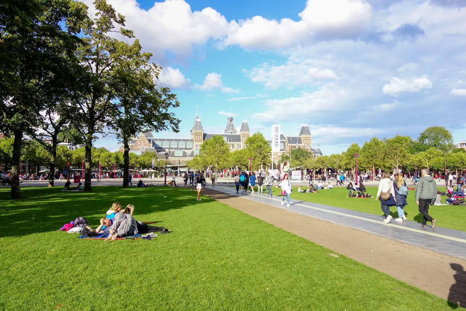 People relaxing in a sunny park with a grand building