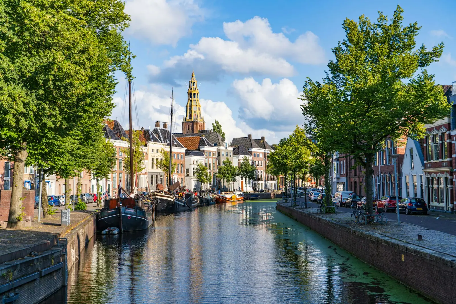 Boat on river near green trees and buildings during daytime