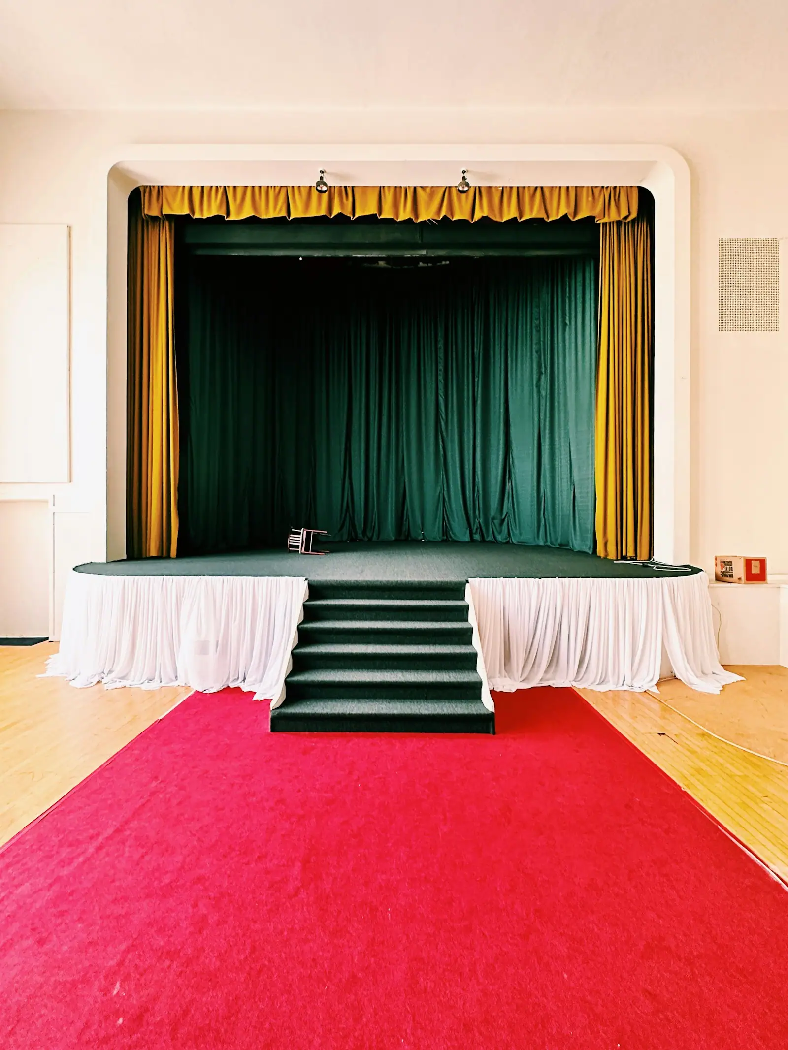 A stage with a red carpet and a green curtain