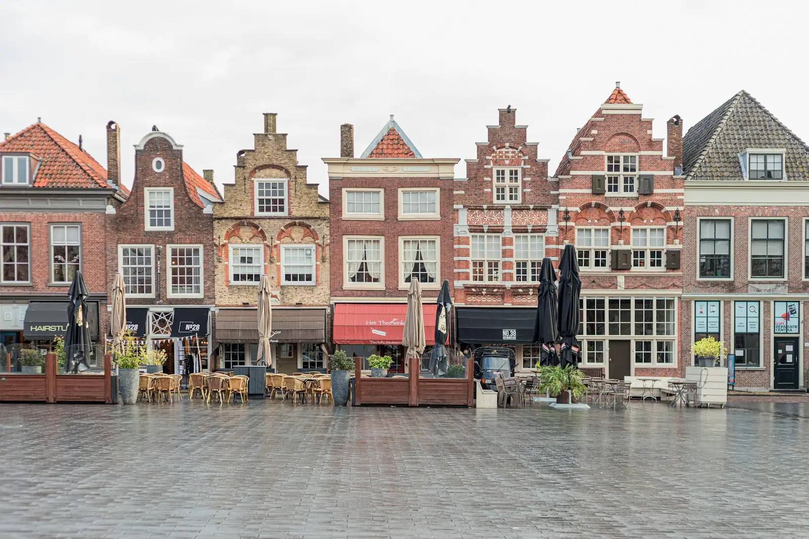 A row of brick buildings with tables and chairs in front of them