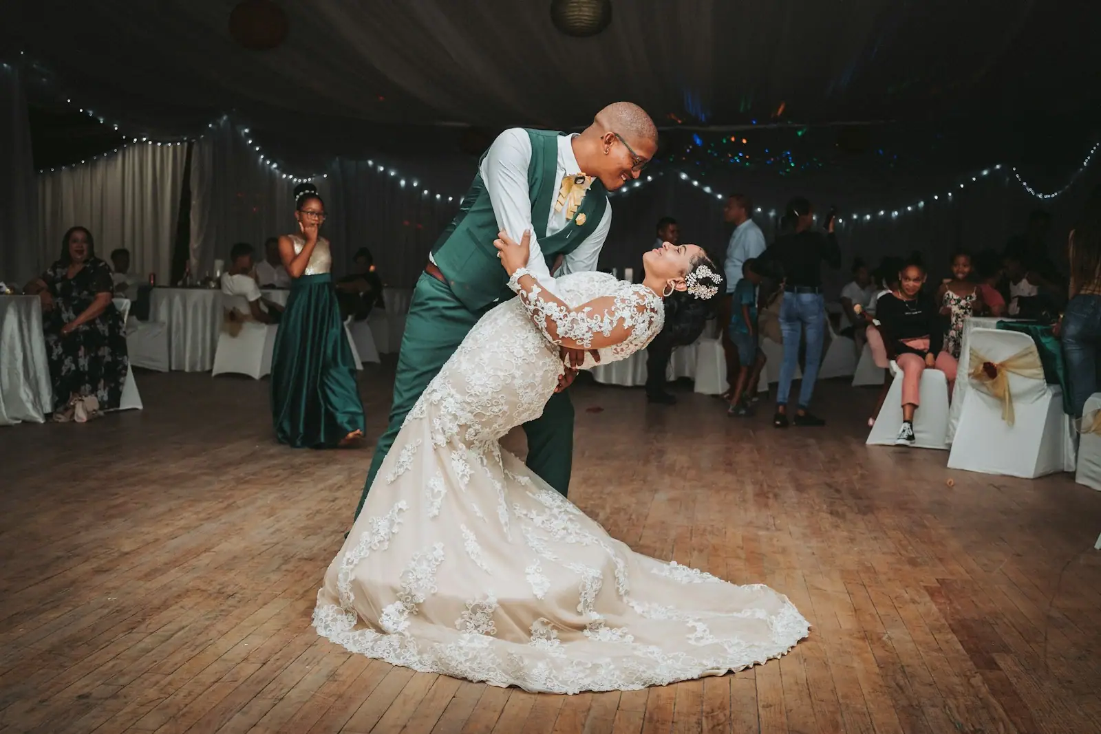 Man in black suit jacket holding woman in white wedding dress