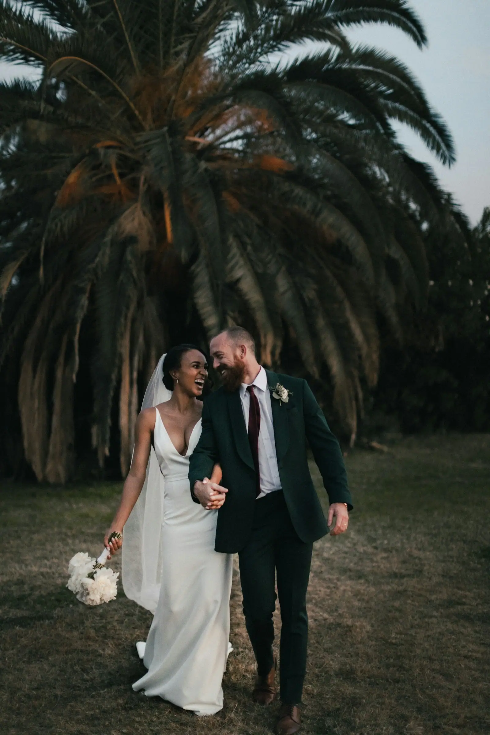 A newly married couple walking through a field