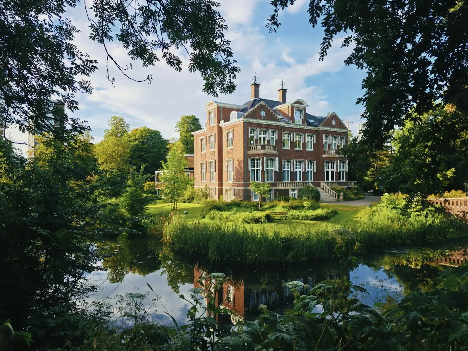 A grand brick mansion reflected in a serene pond