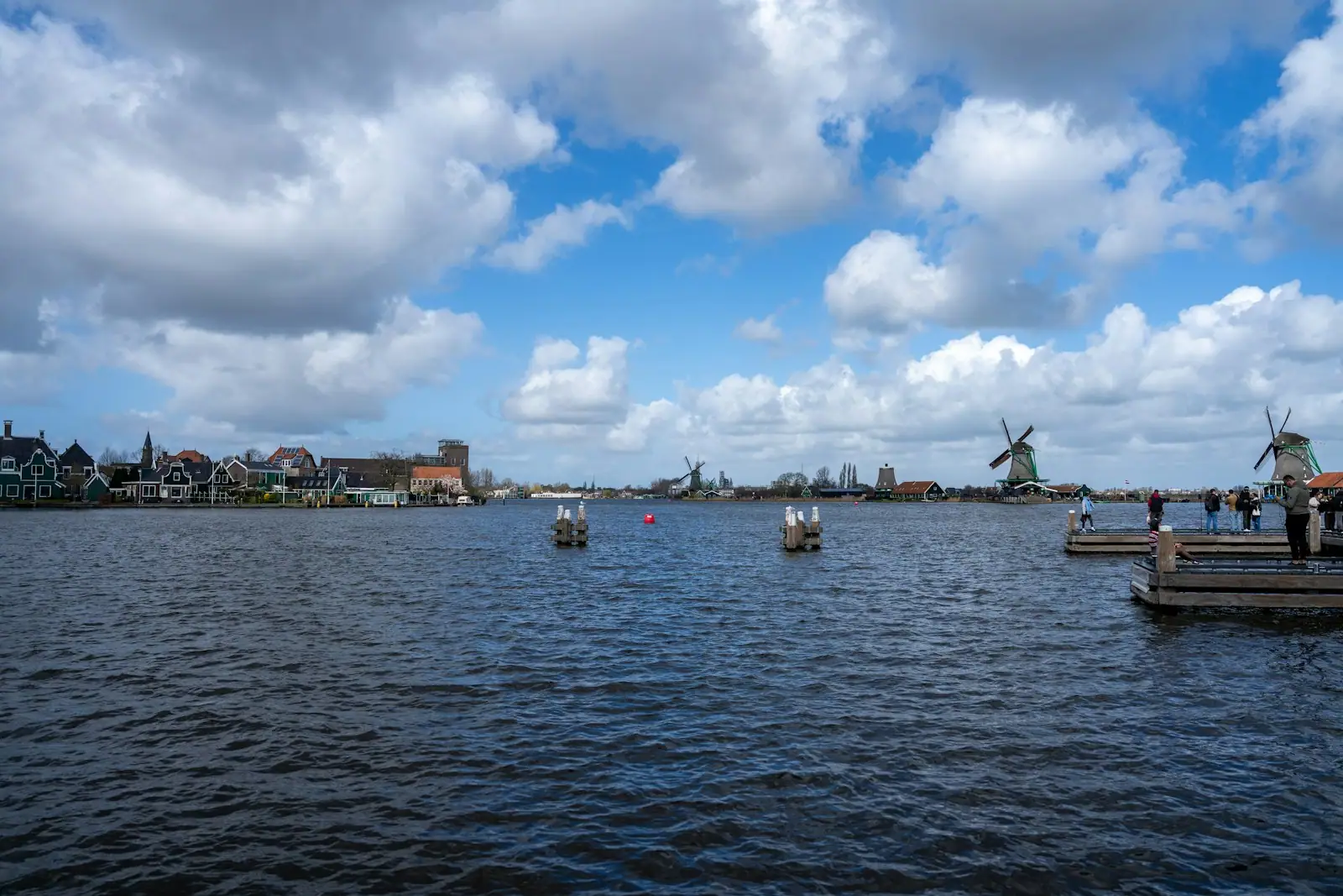 Windmills along the water under a cloudy sky