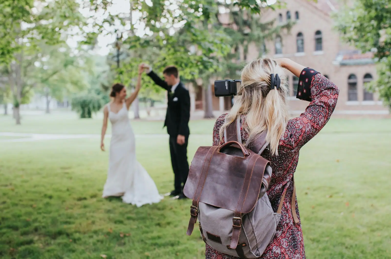 Woman in red and black floral dress carrying black leather shoulder bag