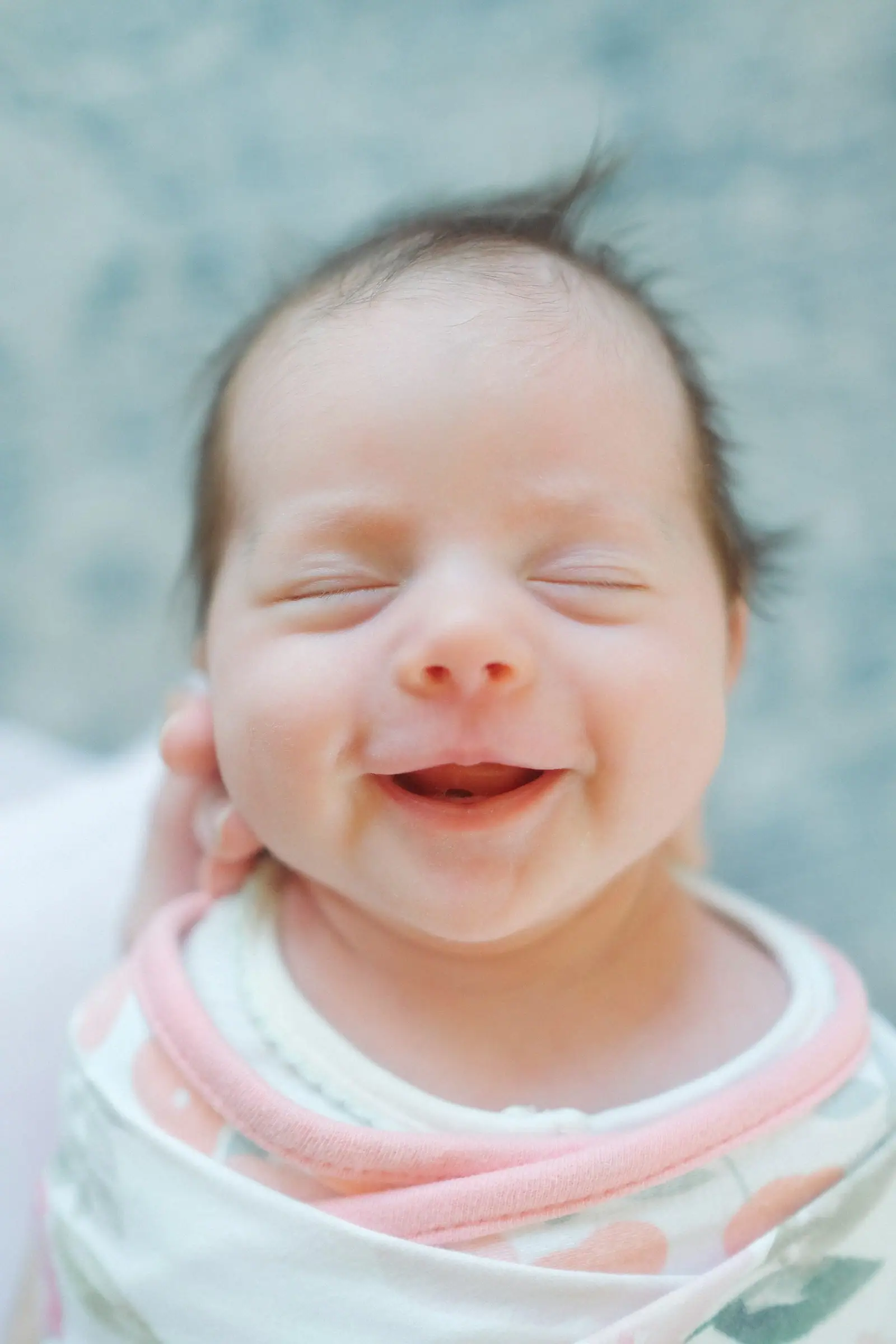 A close up of a baby smiling with its eyes closed