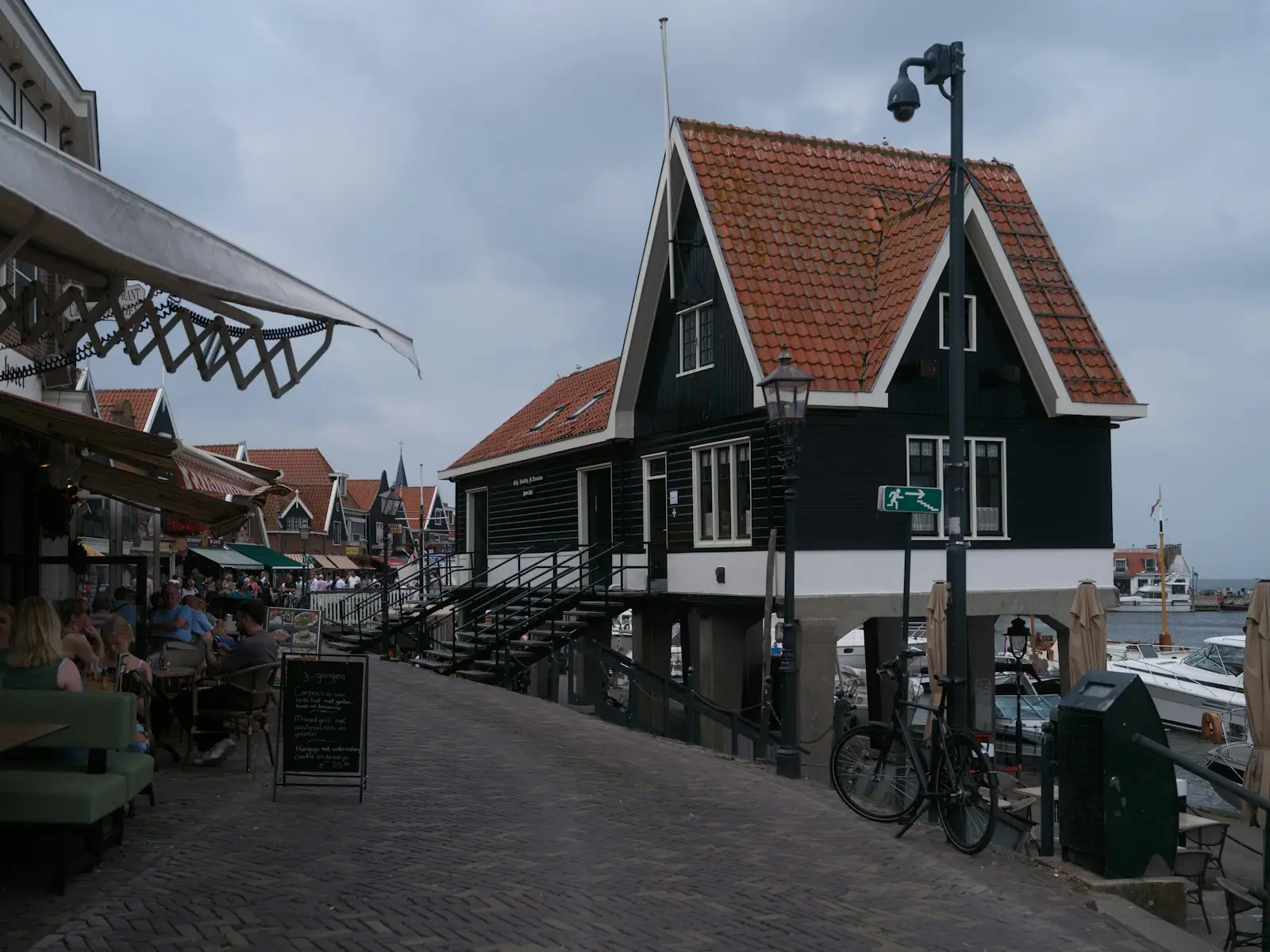 Dark wooden houses on stilts by a waterfront street