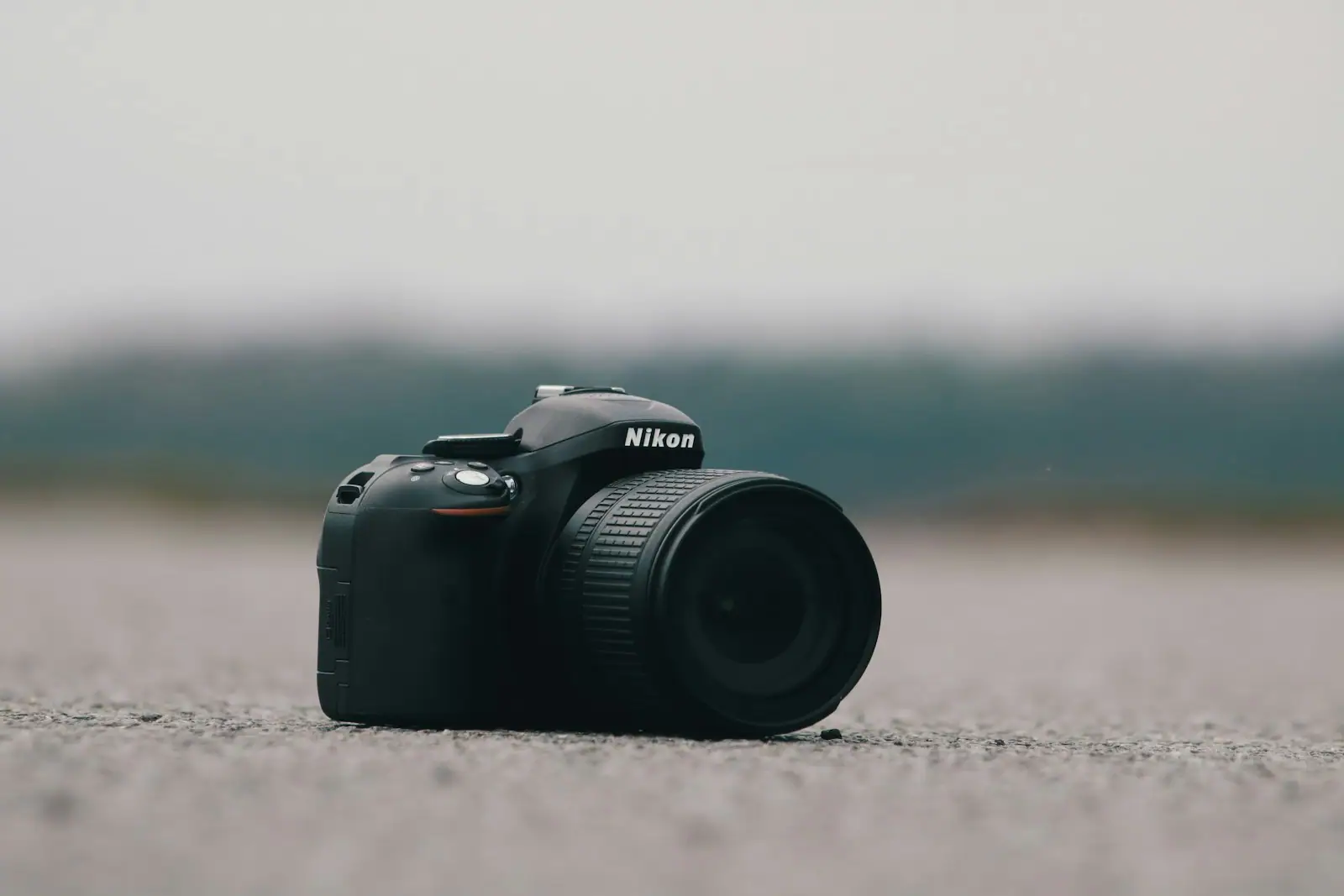Selective focus photography of black Nikon DSLR camera on concrete surface
