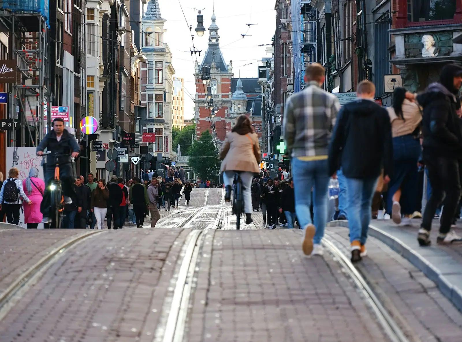 A crowd of people walking down a street next to tall buildings
