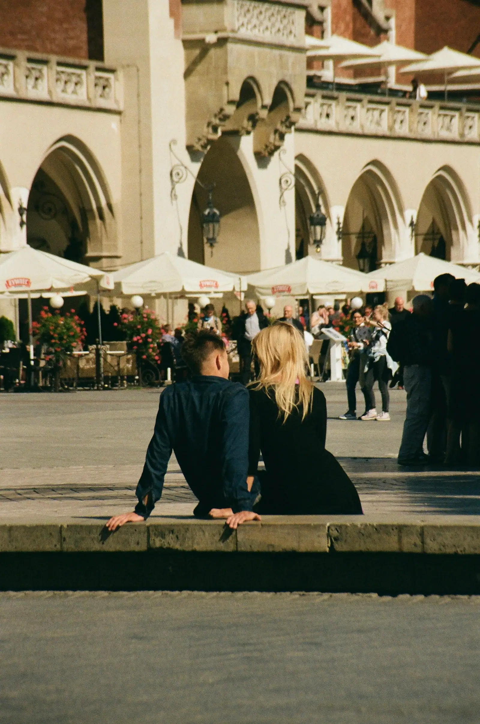 A man and a woman sitting on a bench in front of a building