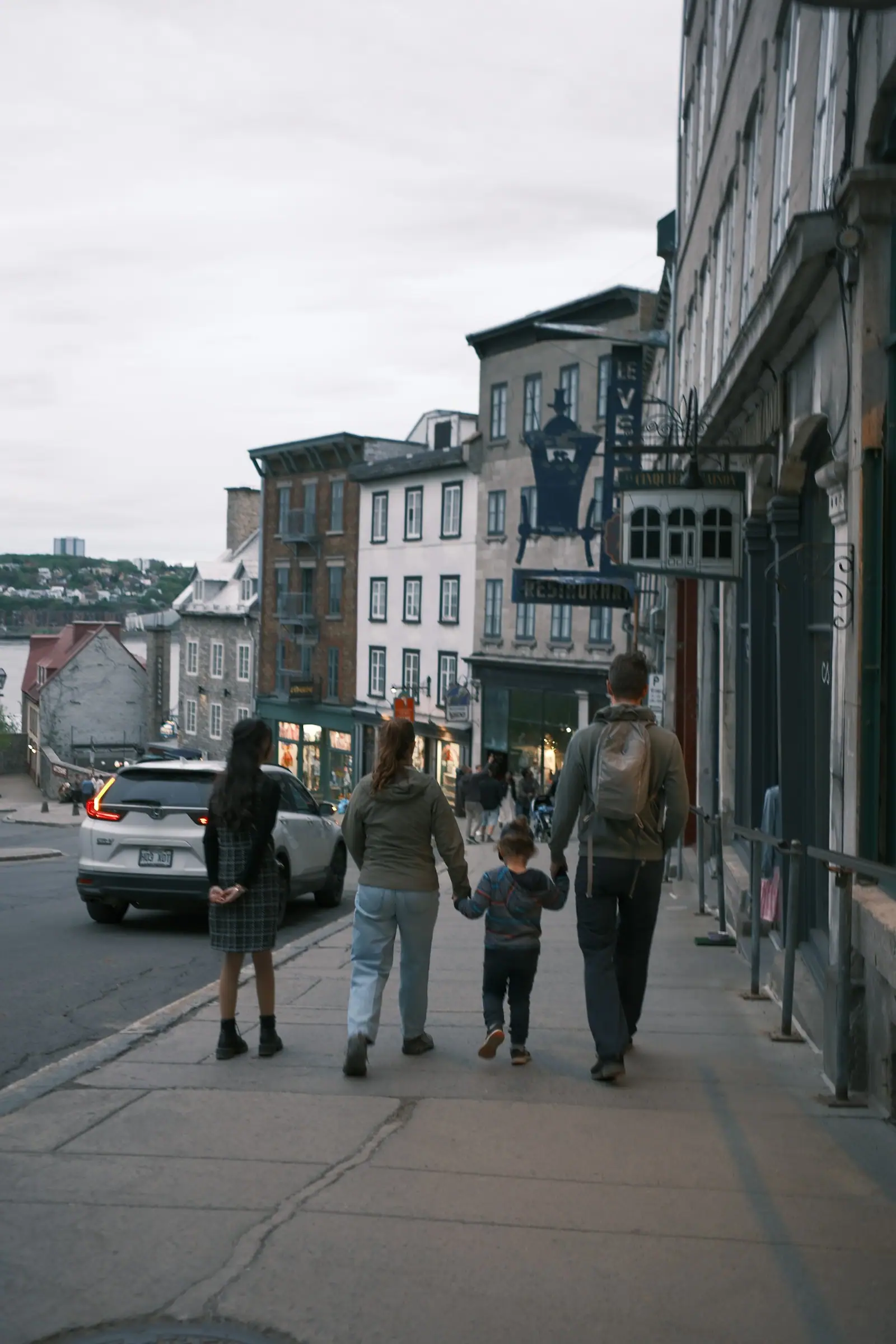 A family walks down a city street at dusk
