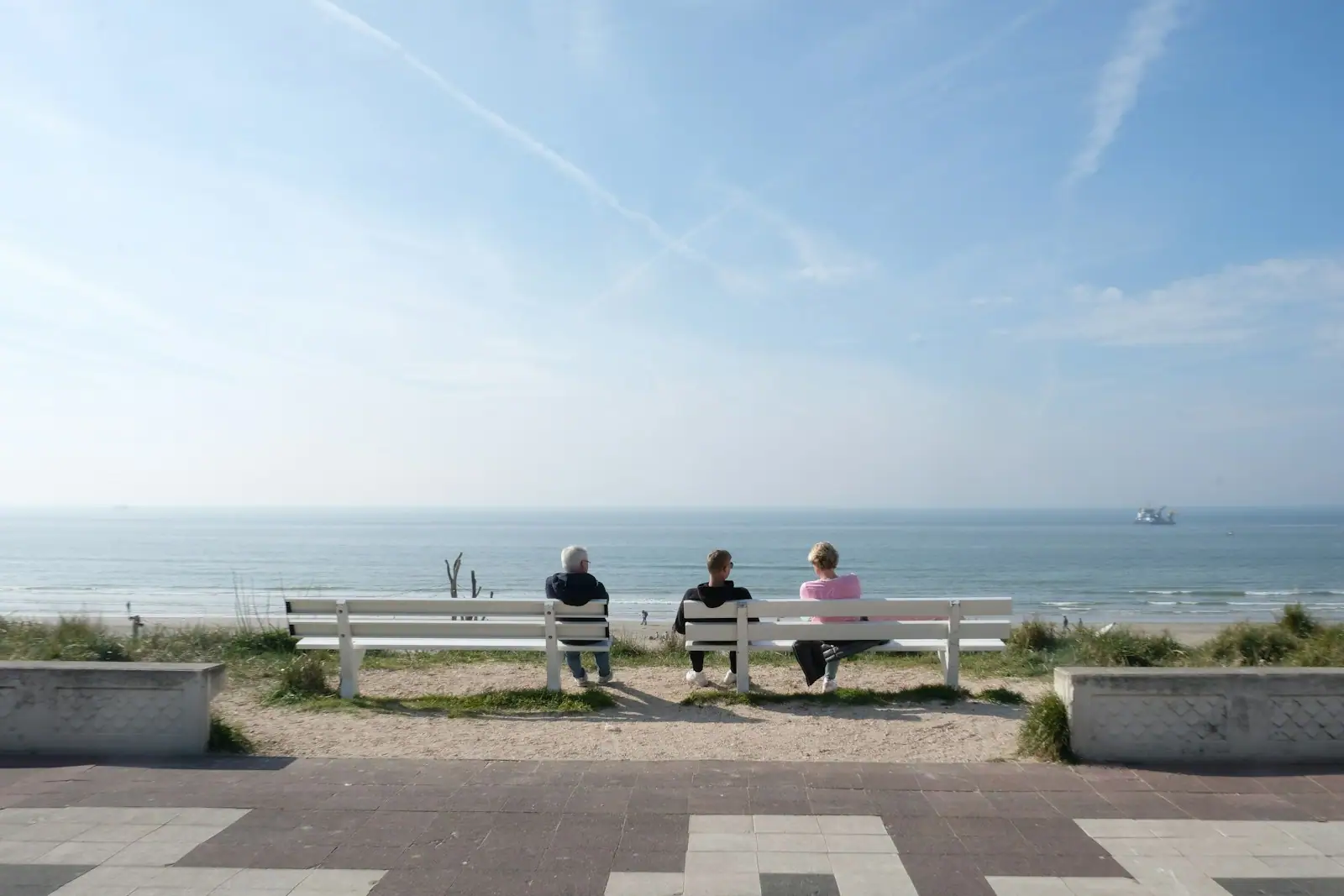 A couple of people sitting on top of a white bench