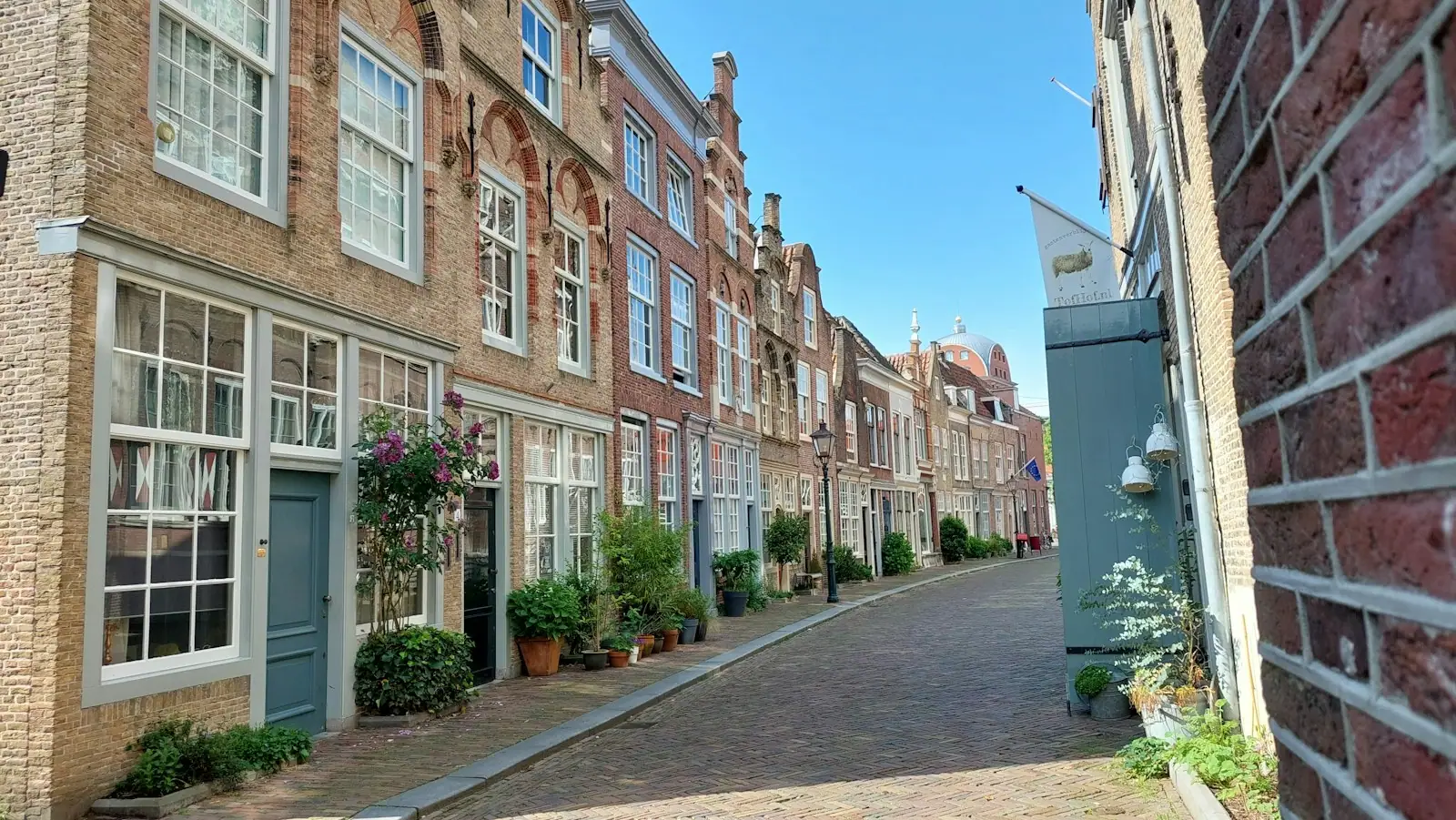 A narrow street with brick buildings and potted plants
