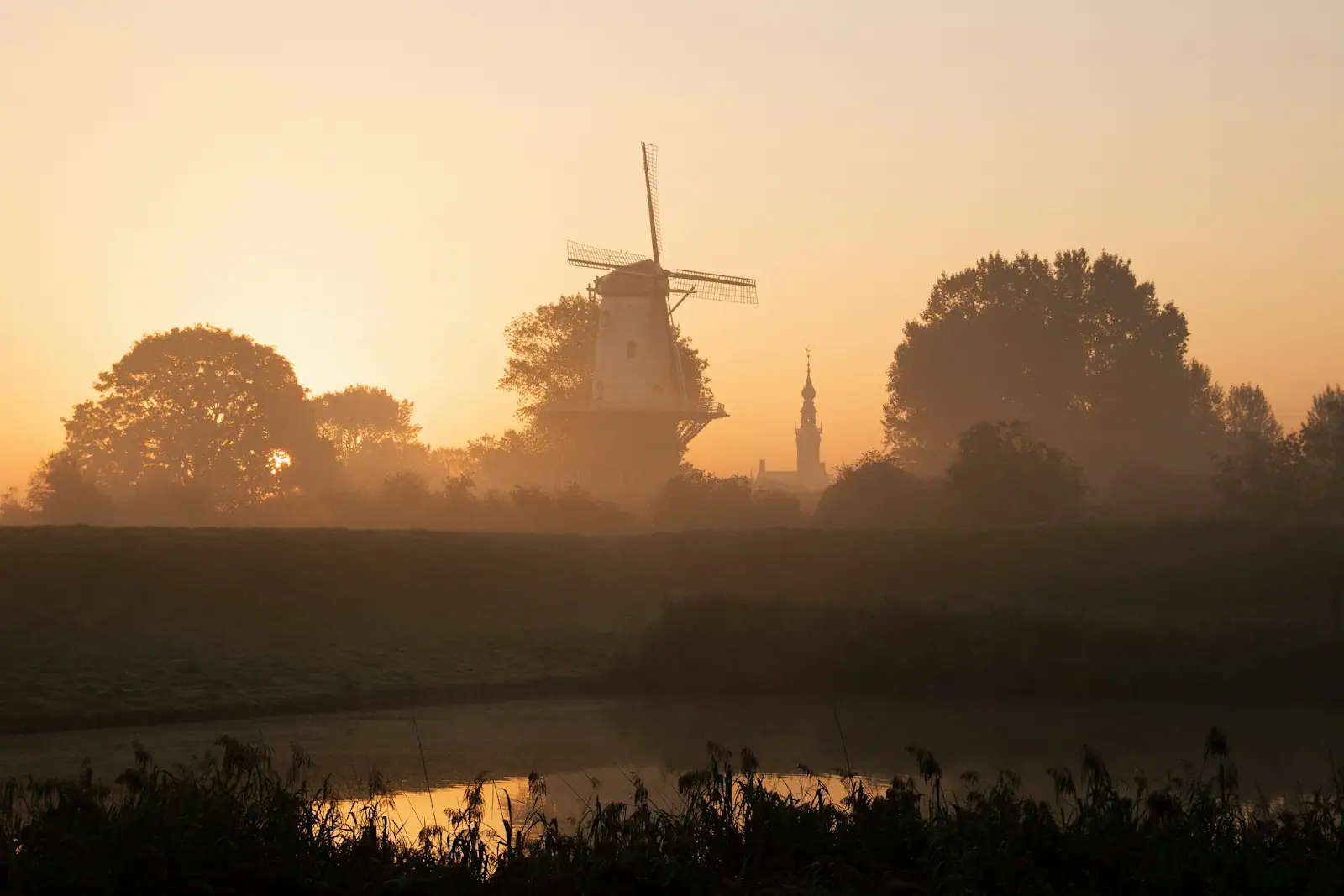 Windmill in a misty field at sunrise