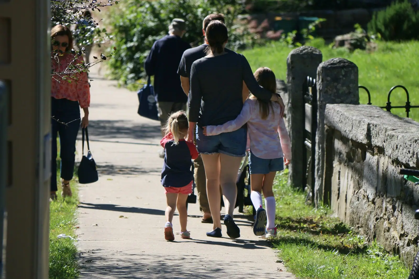 A group of people walking down a sidewalk