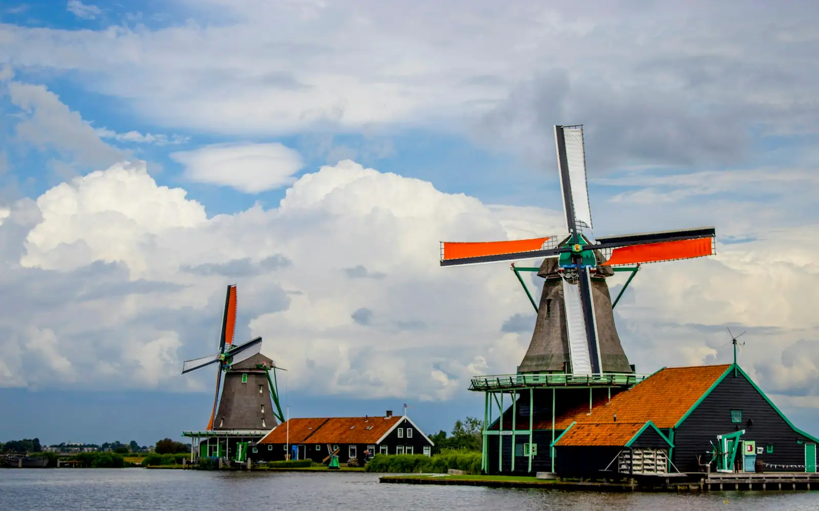 Green and orange windmill under cloudy sky during daytime