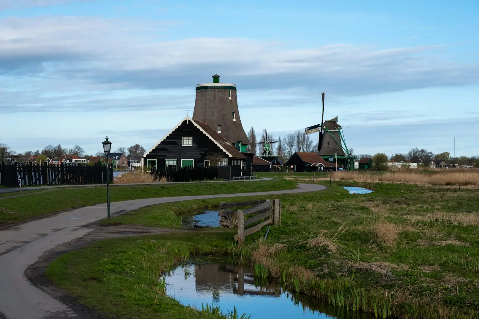Two windmills stand in a rural landscape under blue sky